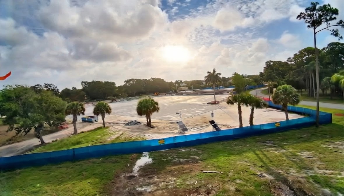 Post-driven blue-screen perimeter around an active graded job site at sunset