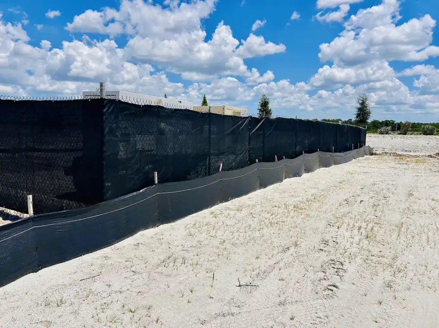 Black-screen temporary fence with silt fence on active job site