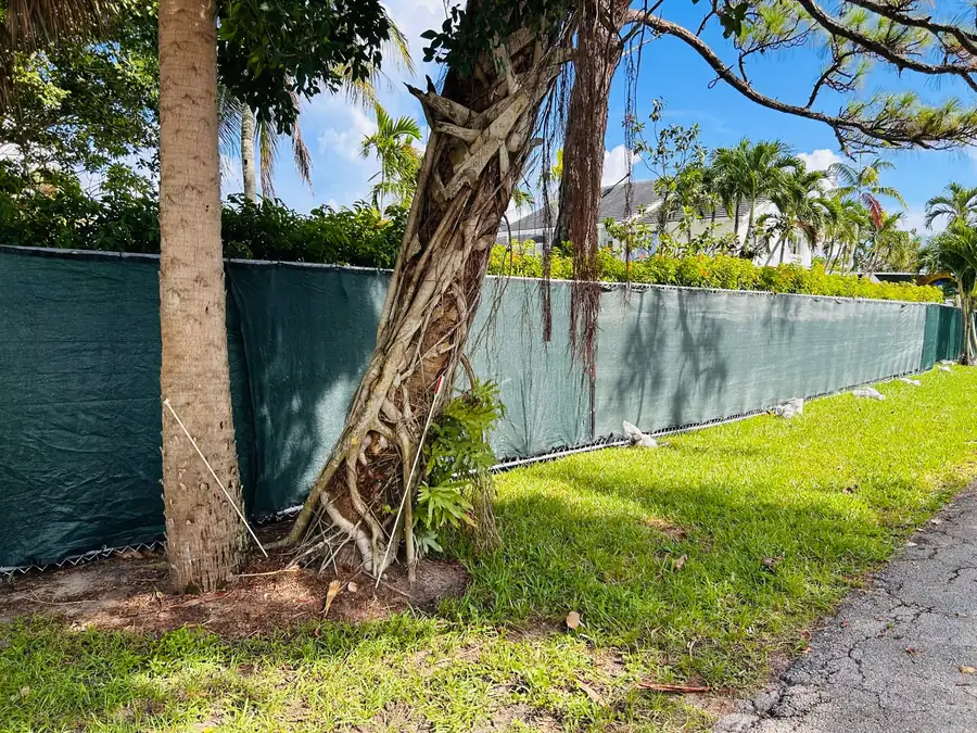 Long temporary fence perimeter with green privacy windscreen along a Florida streetside