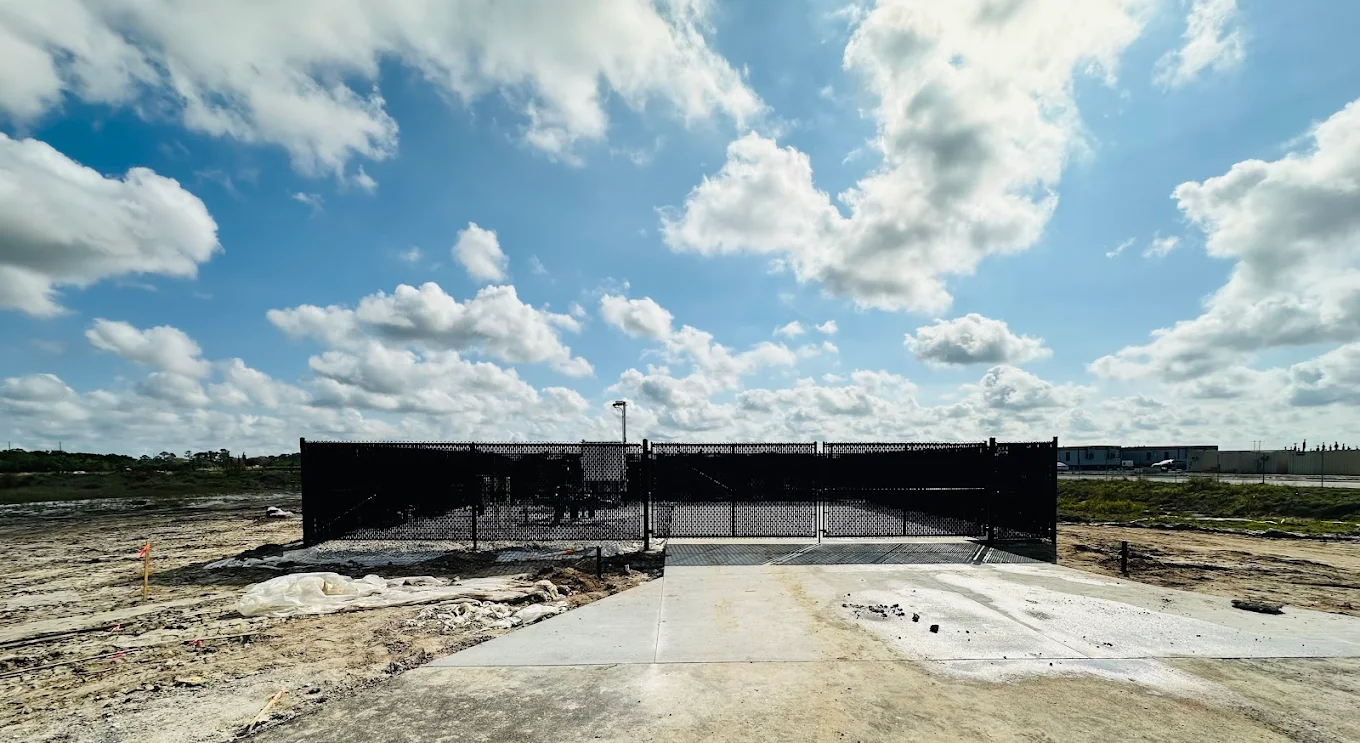 Black commercial cantilever gate and perimeter fence at active site