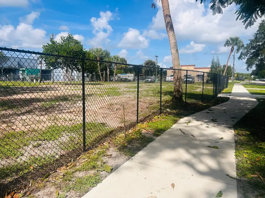 Black temporary chain-link fence installed around a cleared commercial lot
