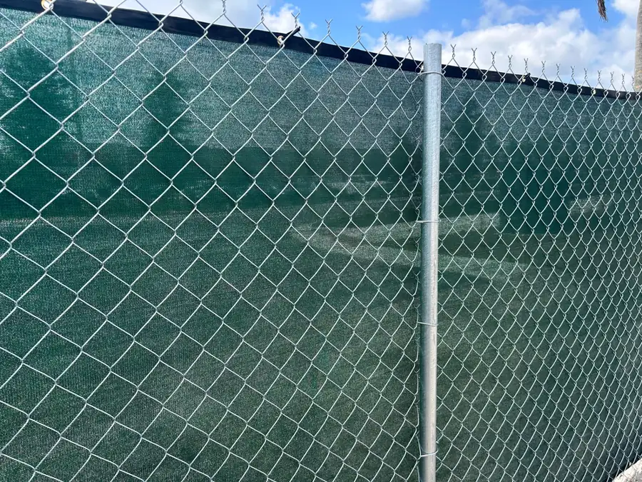 Close view of a post-driven chain-link fence fitted with green windscreen